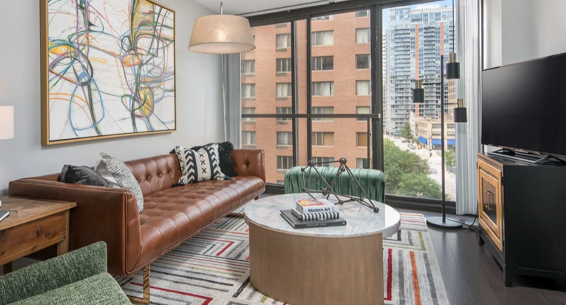Stylish living room with tufted leather sofa, marble coffee table, and bold geometric rug at 777 South State apartments in Chicago