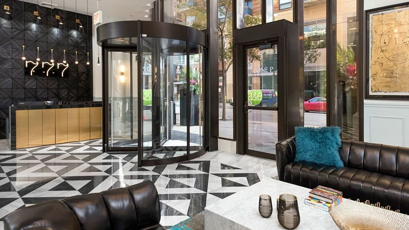 Grand lobby entrance with revolving door, marble floors, chic seating, and concierge desk at 777 South State apartments in Chicago
