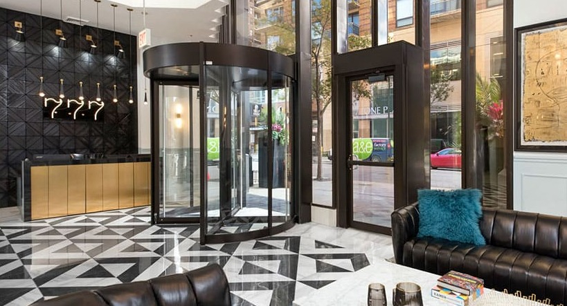 Grand lobby entrance with revolving door, marble floors, chic seating, and concierge desk at 777 South State apartments in Chicago