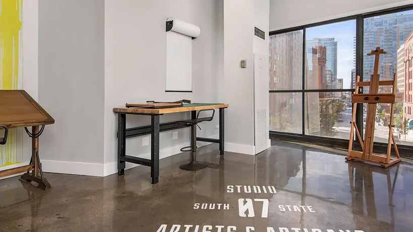 Light-filled makers studio with drafting tables, easel, polished concrete floors, and city views at 777 South State apartments in Chicago