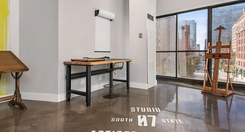 Light-filled makers studio with drafting tables, easel, polished concrete floors, and city views at 777 South State apartments in Chicago