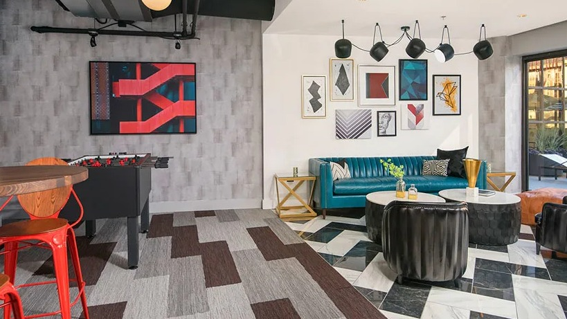 Colorful resident lounge and game room with foosball, gallery-wall art, chic seating, and patio access at 777 South State apartments in Chicago