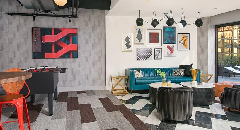 Colorful resident lounge and game room with foosball, gallery-wall art, chic seating, and patio access at 777 South State apartments in Chicago