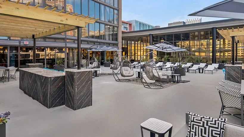 Expansive outdoor terrace with dining tables, swing chairs, lounge seating, and sun umbrellas at 777 South State apartments in Chicago