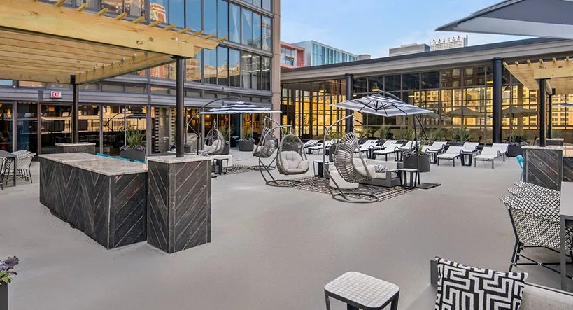 Expansive outdoor terrace with dining tables, swing chairs, lounge seating, and sun umbrellas at 777 South State apartments in Chicago