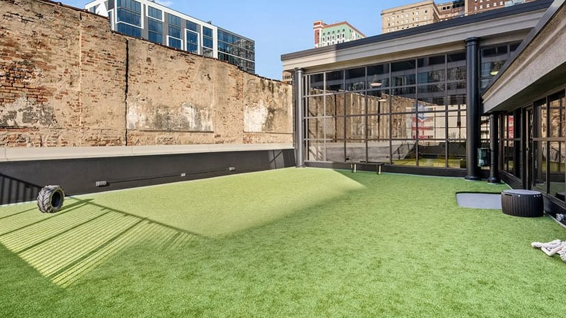 Rooftop turf fitness lawn for bootcamps and outdoor workouts beside glass-walled amenity spaces at 777 South State apartments in Chicago