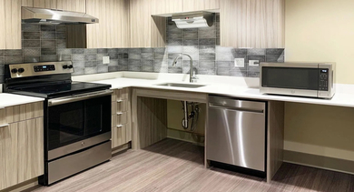 Contemporary community kitchen with long counters, open knee space, tile backsplash, and stainless appliances at 820 Michigan apartments in Chicago