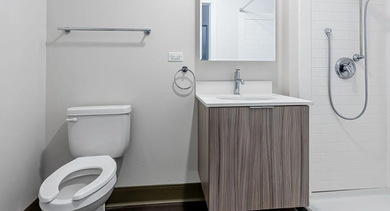 Contemporary bathroom with floating vanity, tiled walk-in shower with handheld sprayer, and chrome fixtures at 820 Michigan apartments in Chicago