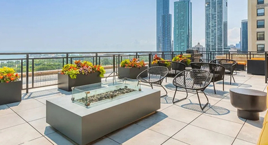 Rooftop lounge with fire table, planters, and expansive skyline and lake views at 820 Michigan apartments in Chicago