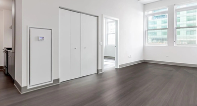 Spacious living room with tall ceilings, wide-plank flooring, and large windows bringing natural light at 820 Michigan apartments in Chicago