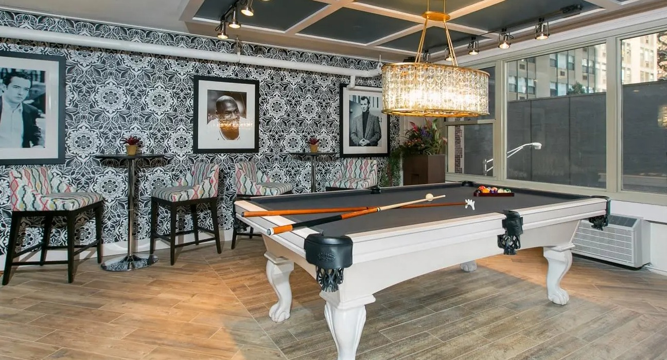 Billiards room with a classic pool table, crystal chandelier, patterned wallpaper, and cafe seating at 860 N Dewitt Apartments in Chicago