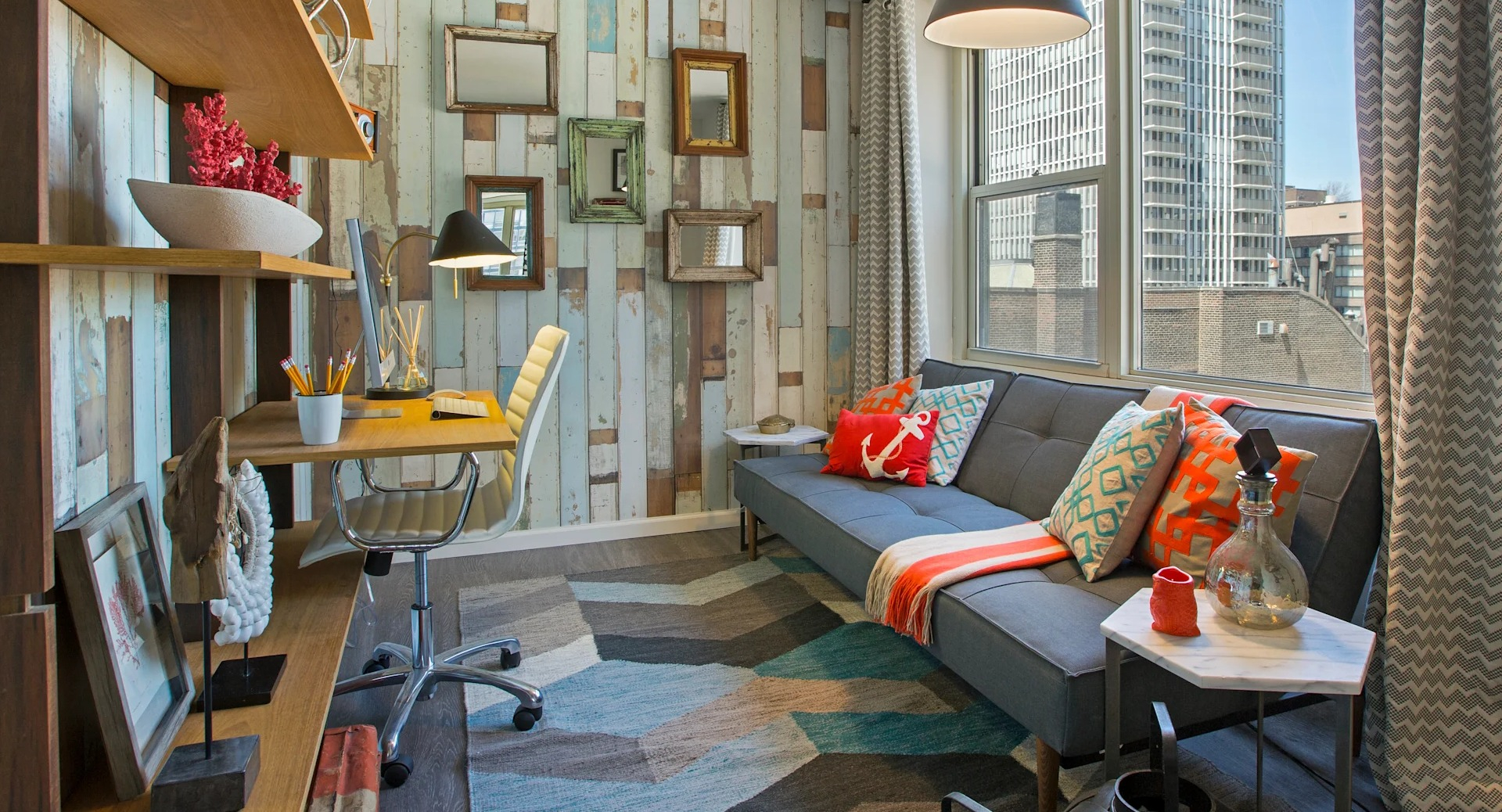 Cozy den or home office with built-in desk, floating shelves, patterned accent wall, and sofa by a window at 860 N Dewitt Apartments in Chicago