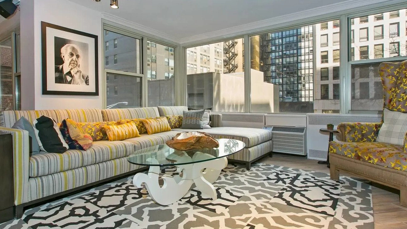 Cozy resident living lounge with large sectional sofa, patterned rug, armchair, and city views at 860 N Dewitt Apartments in Chicago
