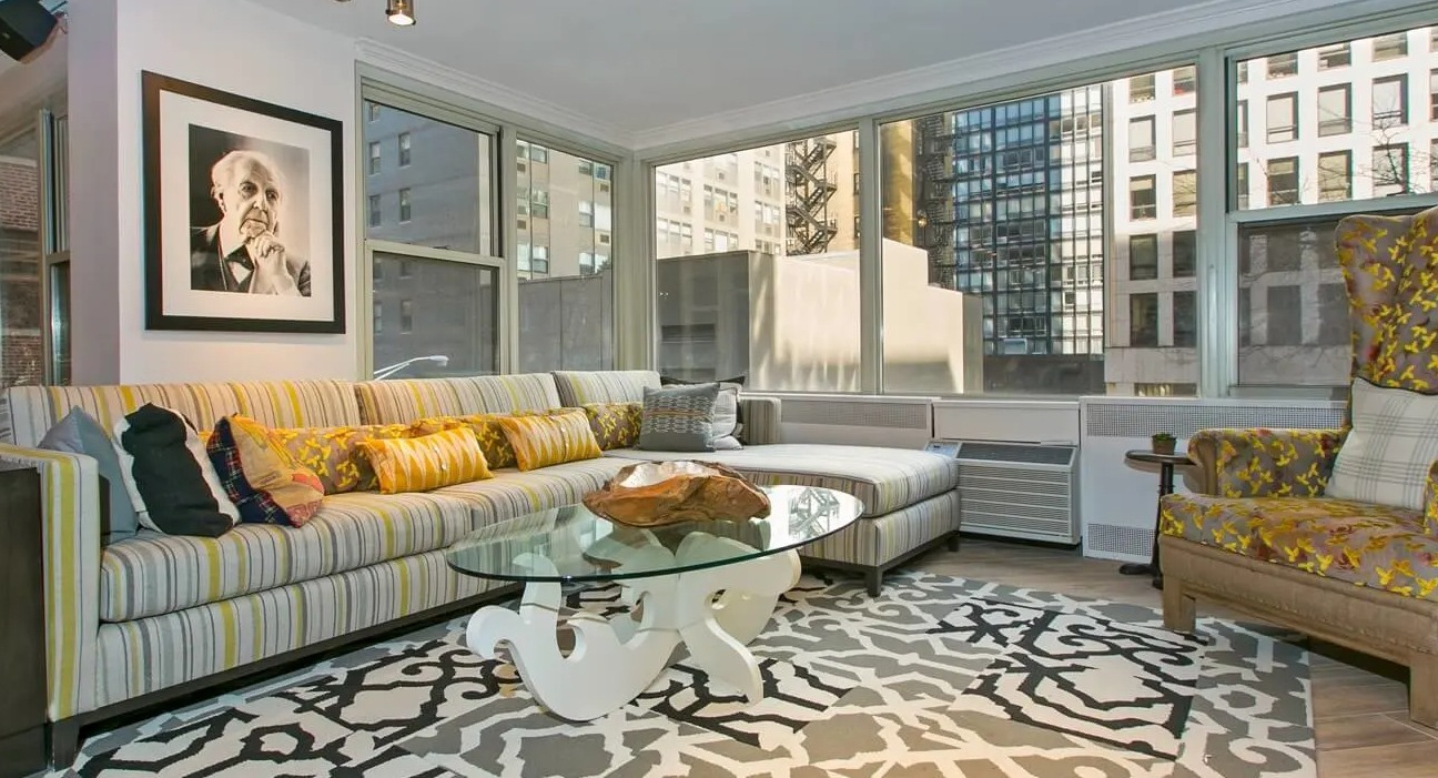 Cozy resident living lounge with large sectional sofa, patterned rug, armchair, and city views at 860 N Dewitt Apartments in Chicago