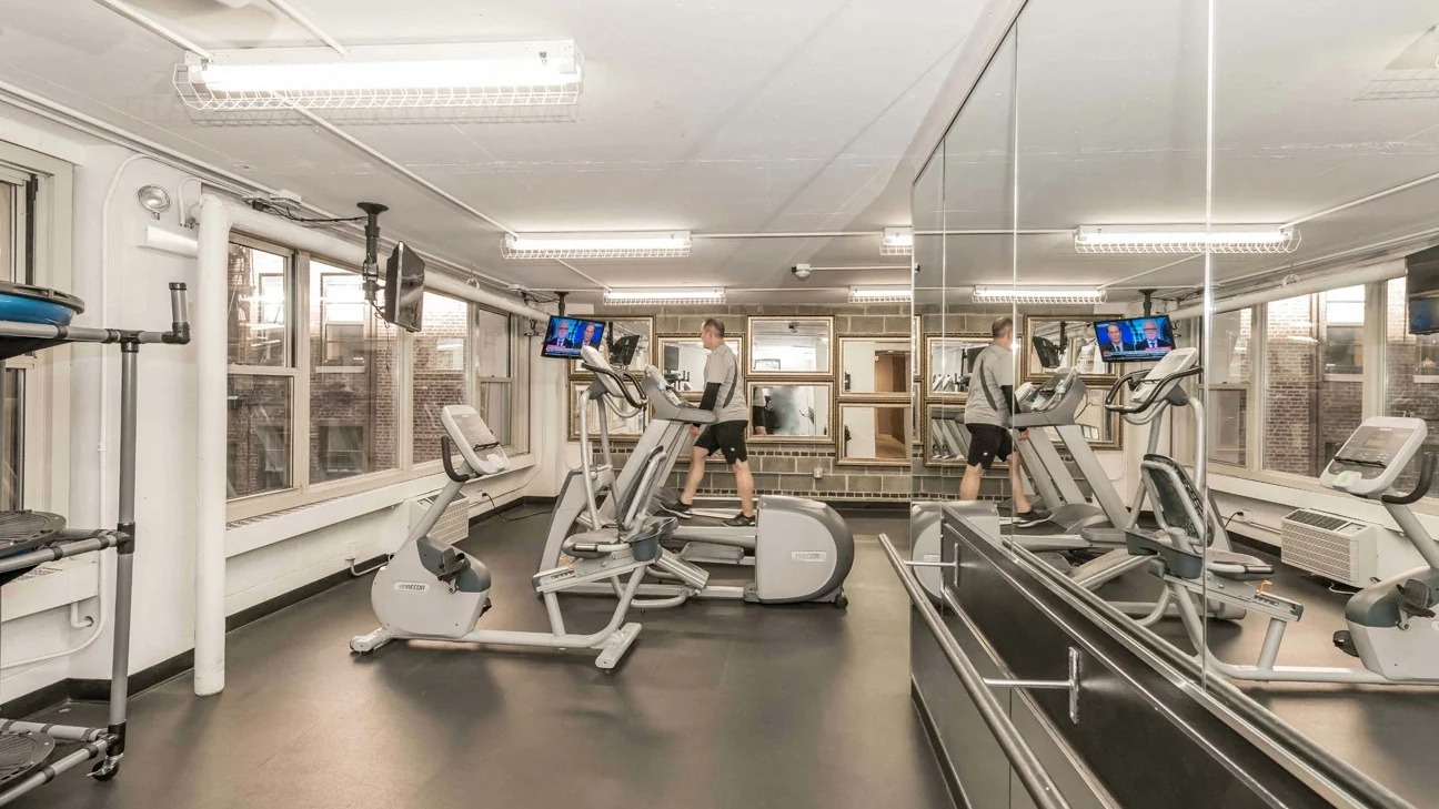 Fitness center cardio room with treadmills, ellipticals, mirrors, and TVs in a bright space at 860 N Dewitt Apartments in Chicago