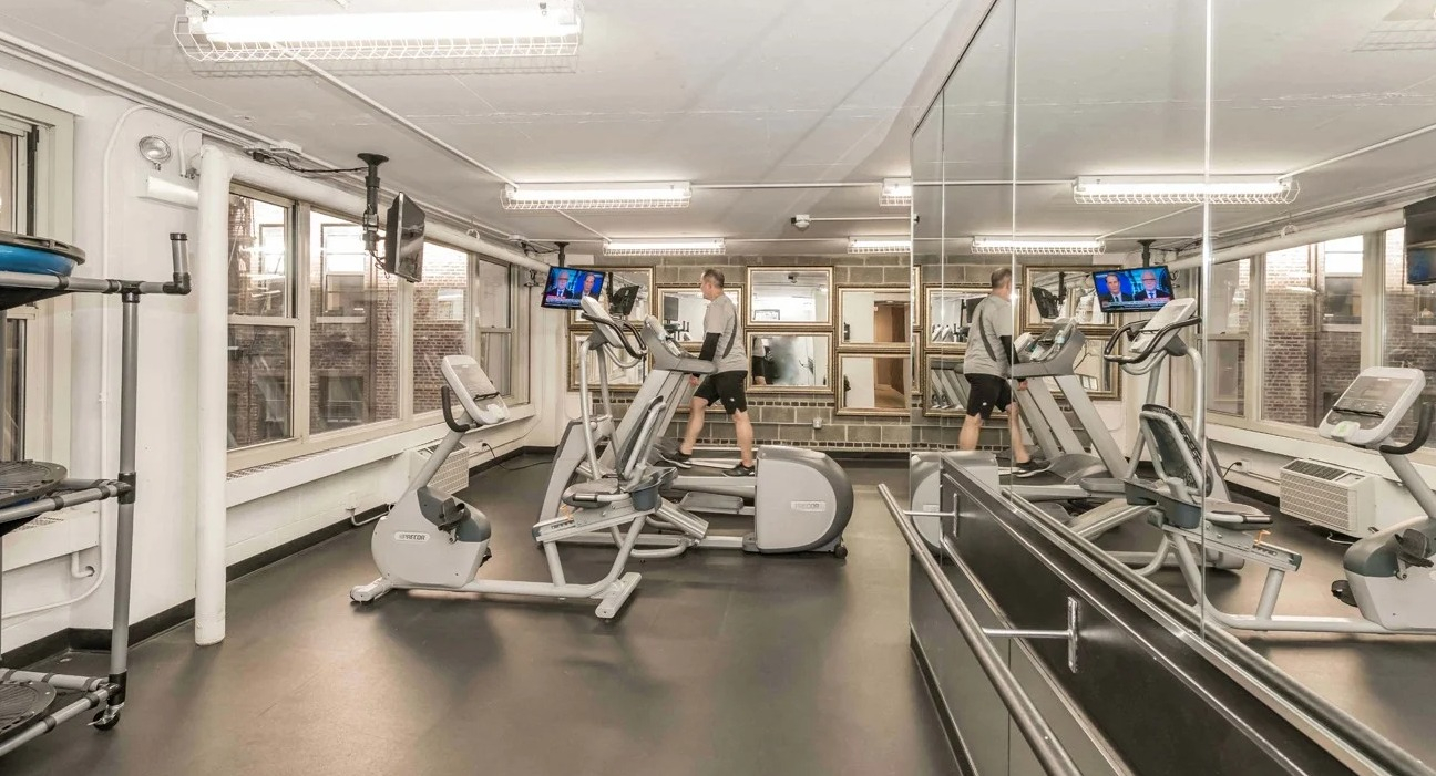 Fitness center cardio room with treadmills, ellipticals, mirrors, and TVs in a bright space at 860 N Dewitt Apartments in Chicago