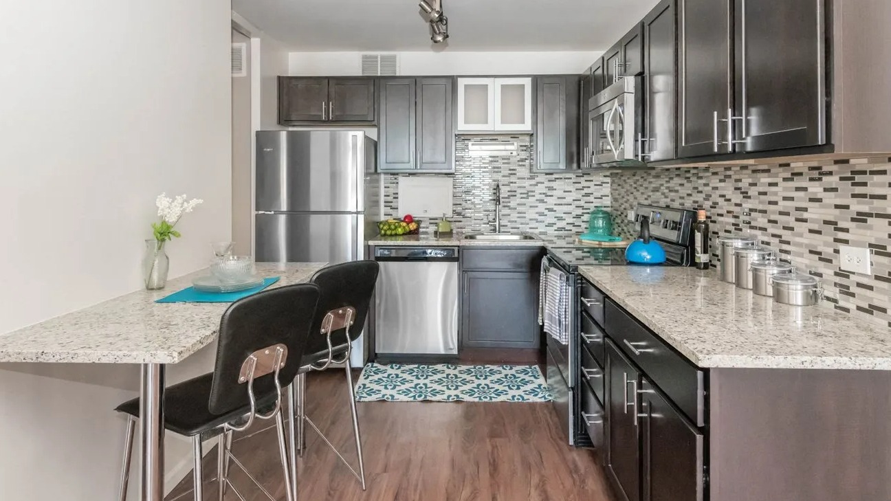 Kitchen with granite counters, mosaic backsplash, cabinets, stainless appliances, and breakfast bar at 860 N Dewitt Apartments in Chicago