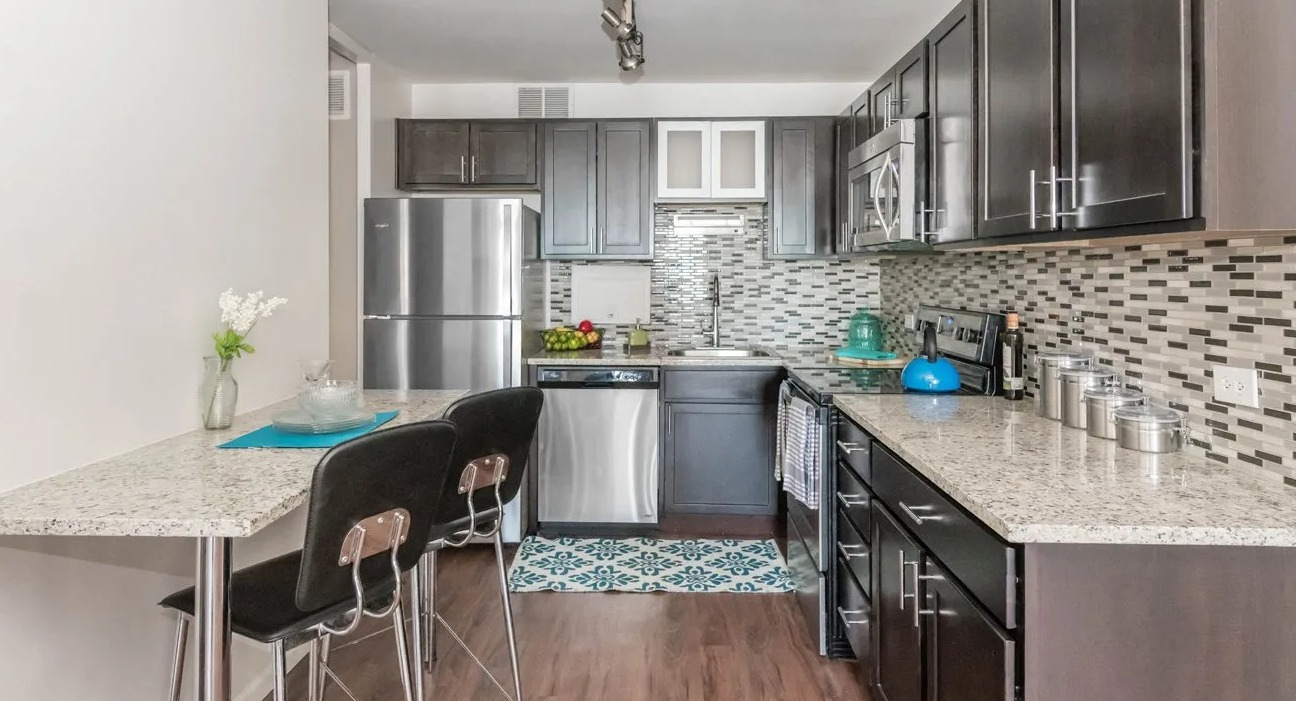 Kitchen with granite counters, mosaic backsplash, cabinets, stainless appliances, and breakfast bar at 860 N Dewitt Apartments in Chicago