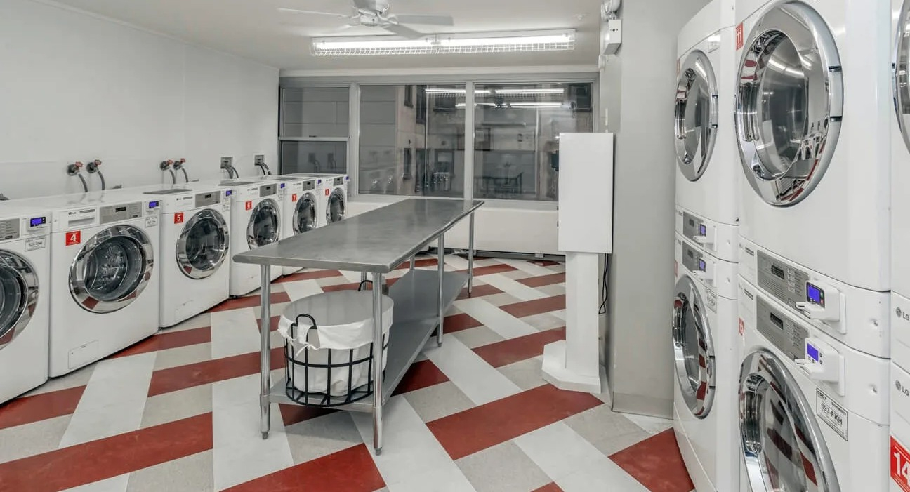 Bright on-site laundry room with multiple washers and dryers, folding table, and checkerboard floors at 860 N Dewitt Apartments in Chicago