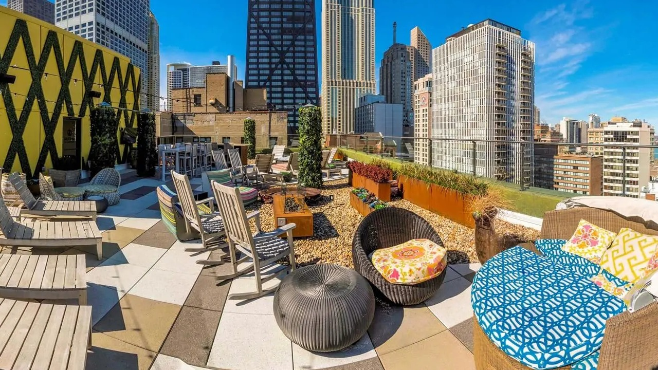 Rooftop lounge with daybeds, loungers, planters, and skyline views near the John Hancock Center at 860 N Dewitt Apartments in Chicago