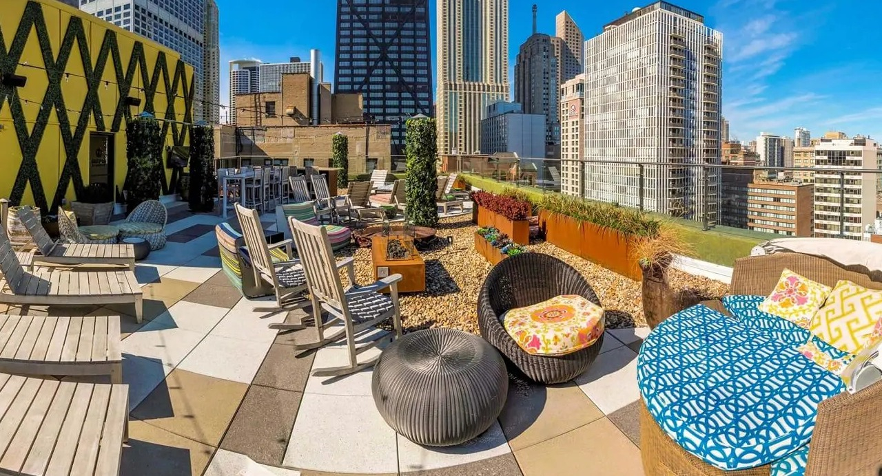 Rooftop lounge with daybeds, loungers, planters, and skyline views near the John Hancock Center at 860 N Dewitt Apartments in Chicago