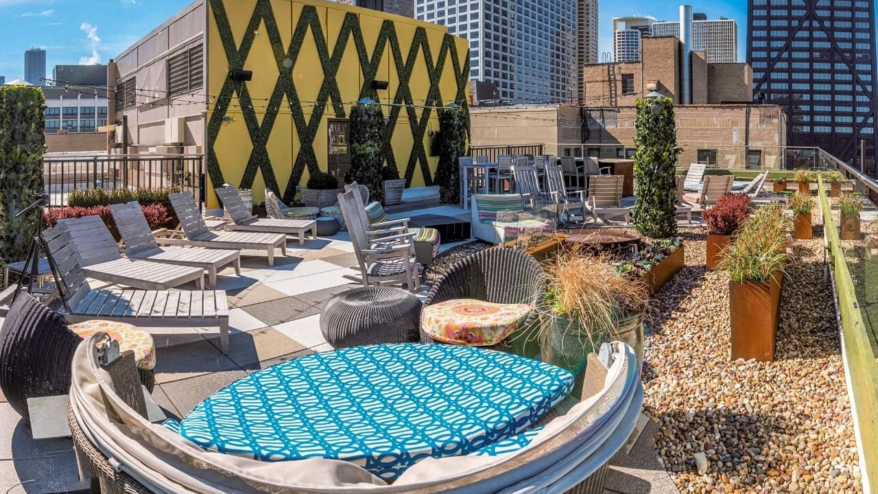 Rooftop sundeck with lounge chairs, greenery, and skyline views at 860 N Dewitt Apartments in Chicago, ideal for sunbathing and outdoor hangouts