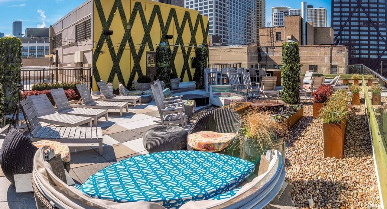 Rooftop sundeck with lounge chairs, greenery, and skyline views at 860 N Dewitt Apartments in Chicago, ideal for sunbathing and outdoor hangouts
