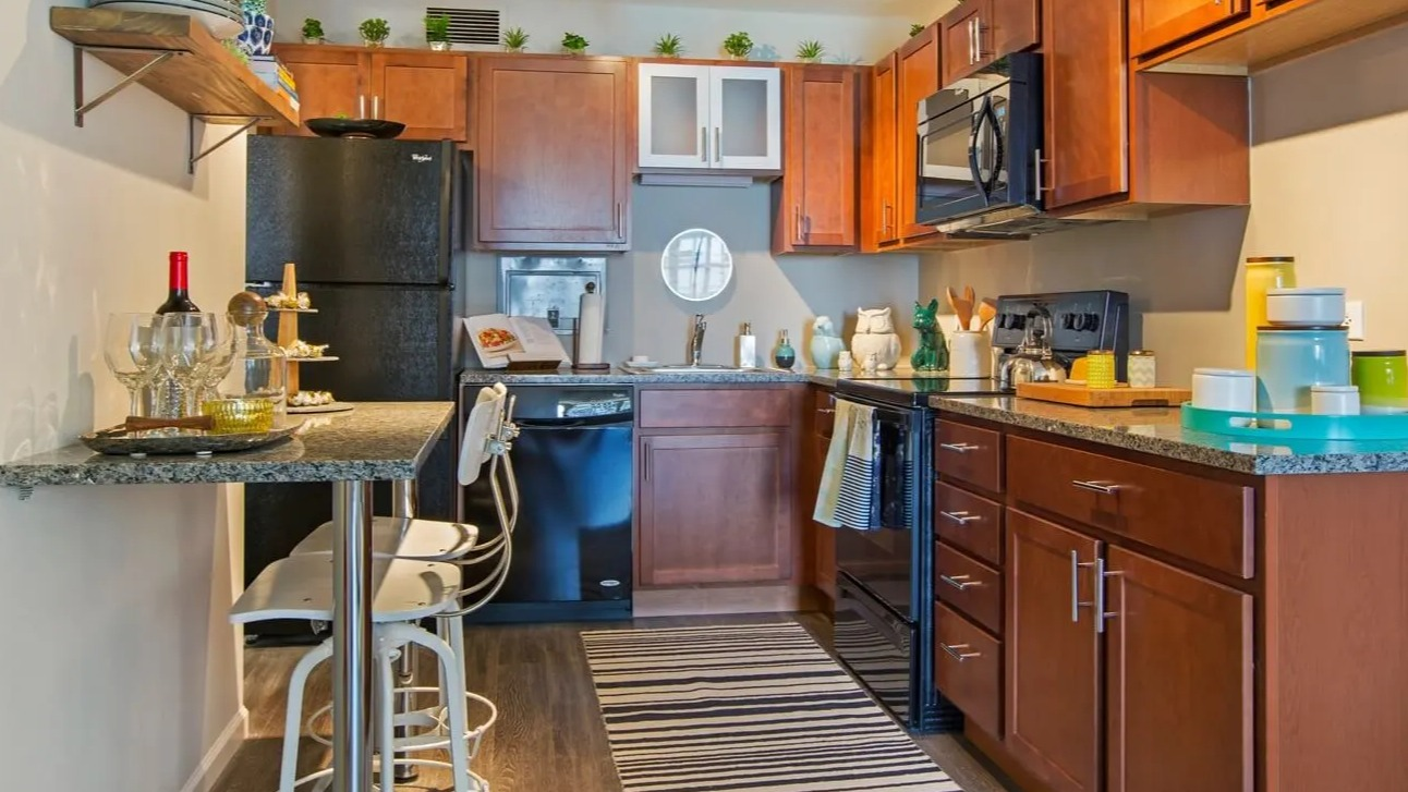 Updated kitchen with warm wood cabinets, granite counters, breakfast bar seating, and modern appliances at 860 N Dewitt Apartments in Chicago