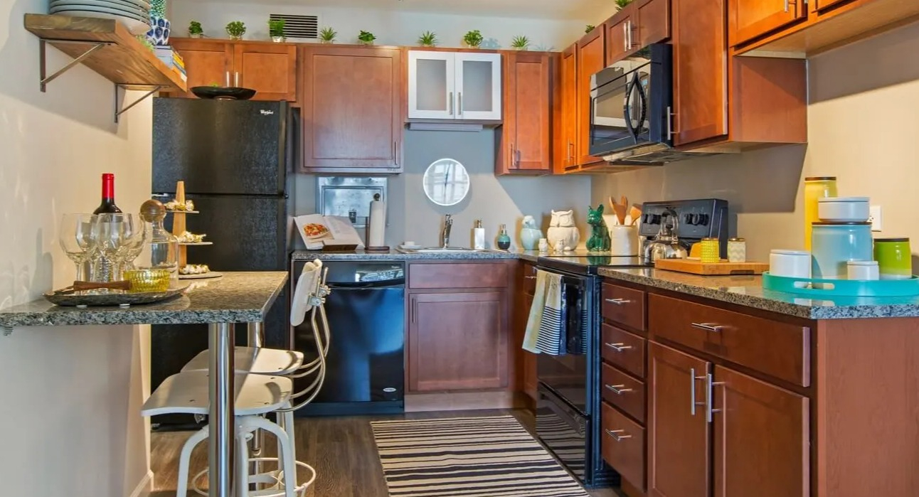 Updated kitchen with warm wood cabinets, granite counters, breakfast bar seating, and modern appliances at 860 N Dewitt Apartments in Chicago