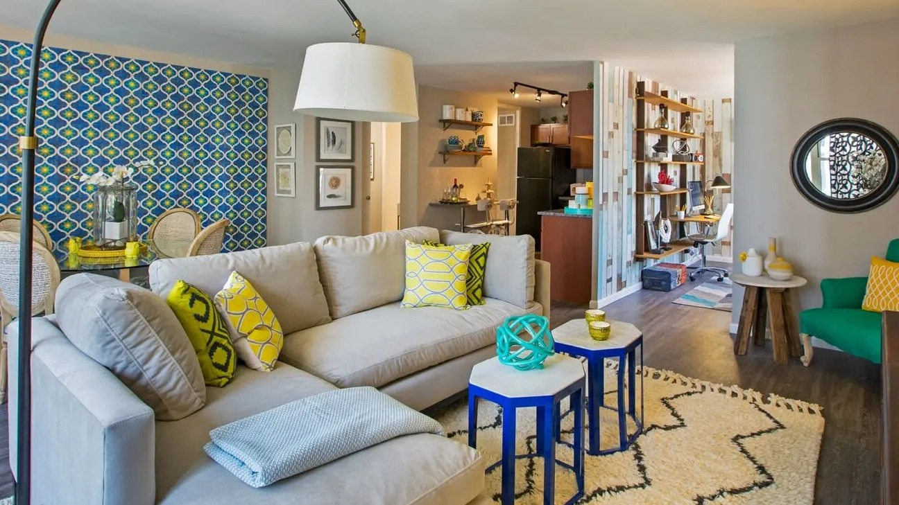 Vibrant living room with sectional sofa, bold accent wall, stylish lighting, and view into dining and kitchen at 860 N Dewitt Apartments in Chicago