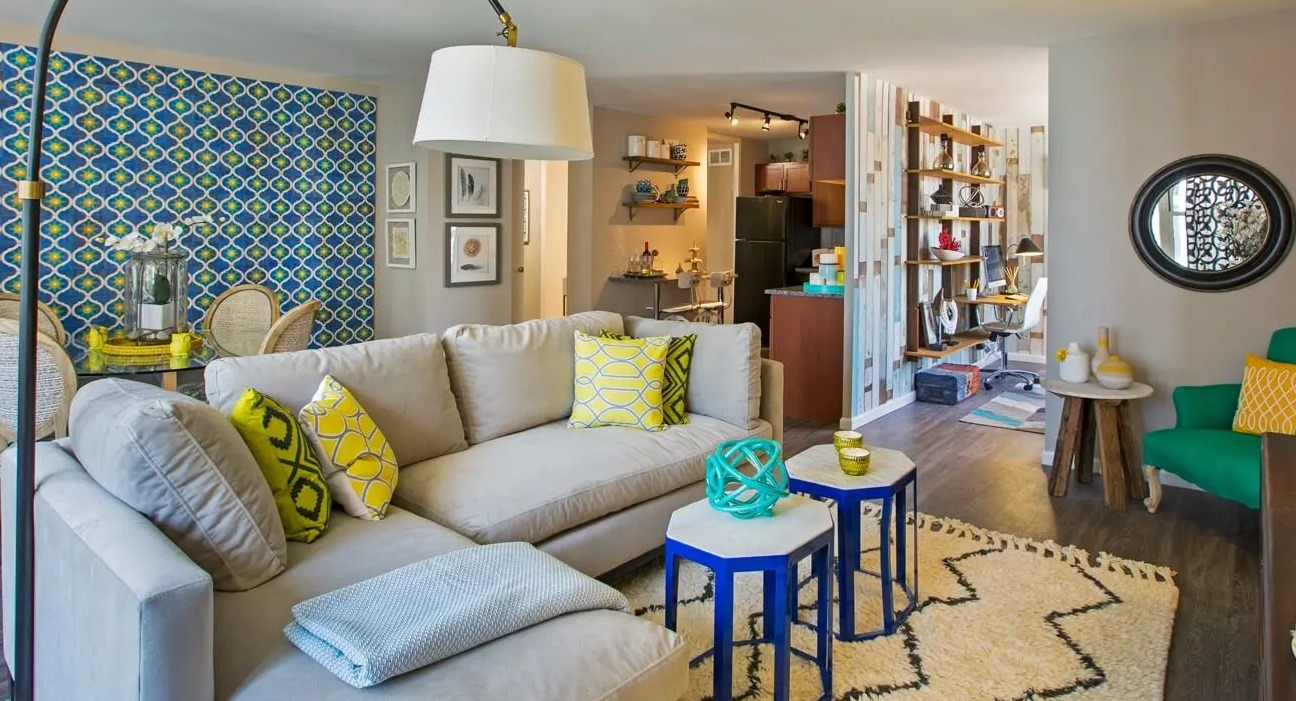 Vibrant living room with sectional sofa, bold accent wall, stylish lighting, and view into dining and kitchen at 860 N Dewitt Apartments in Chicago