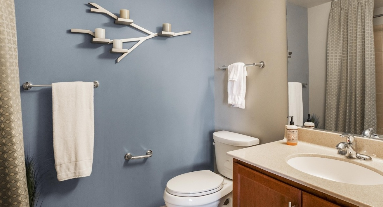 Contemporary bathroom at Alta at K Station in Chicago featuring a blue accent wall, sleek vanity, large mirror, and towel bars for a clean, modern look