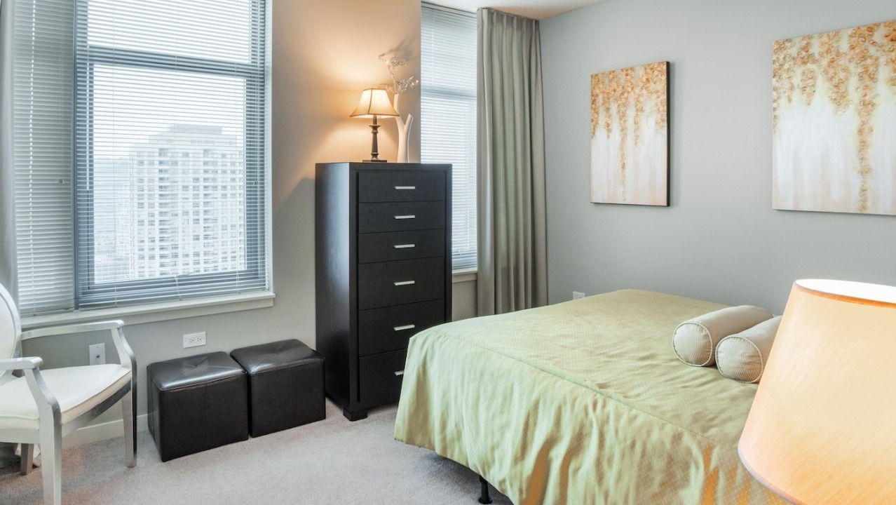 Cozy bedroom at Alta at K Station in Chicago with soft neutral walls, large windows, city views, and contemporary furnishings for a calm, restful space