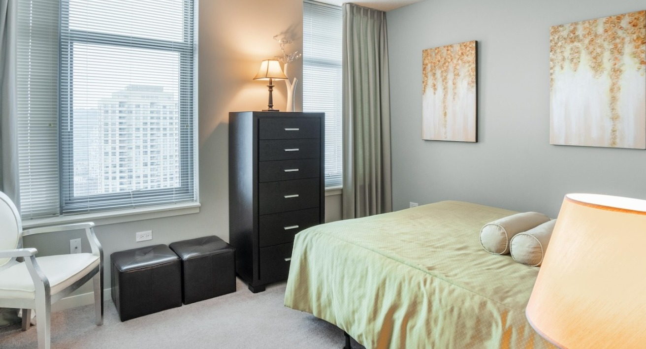 Cozy bedroom at Alta at K Station in Chicago with soft neutral walls, large windows, city views, and contemporary furnishings for a calm, restful space