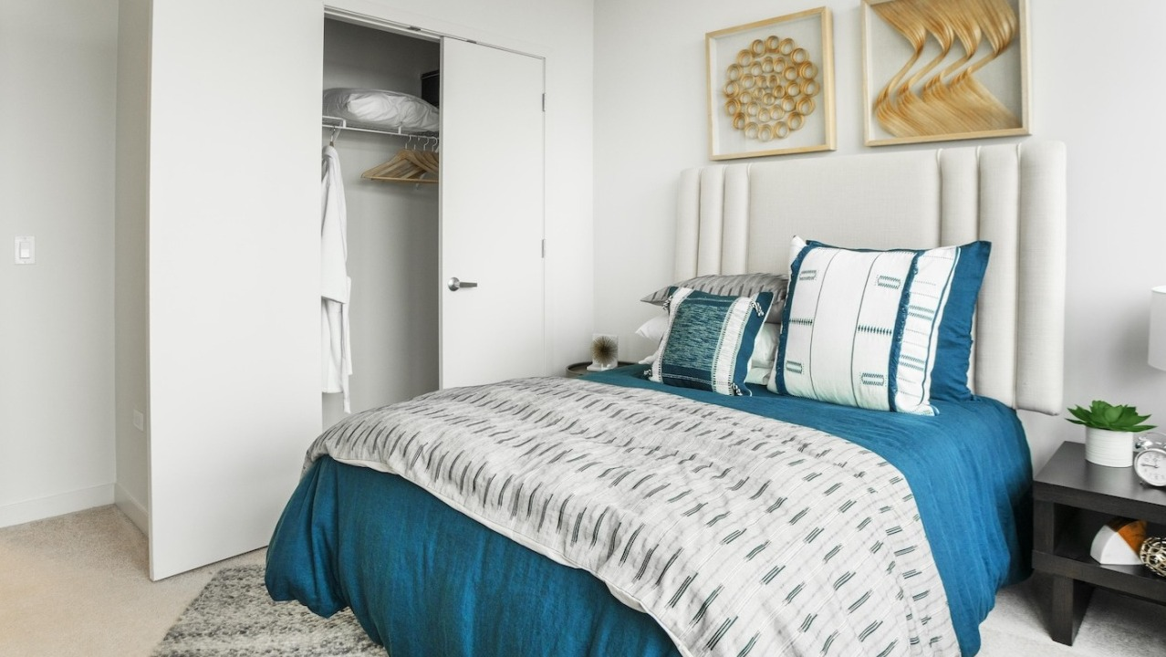 Modern bedroom at Alta at K Station in Chicago featuring a bright interior, upholstered headboard, bold blue bedding, and wall art above the bed