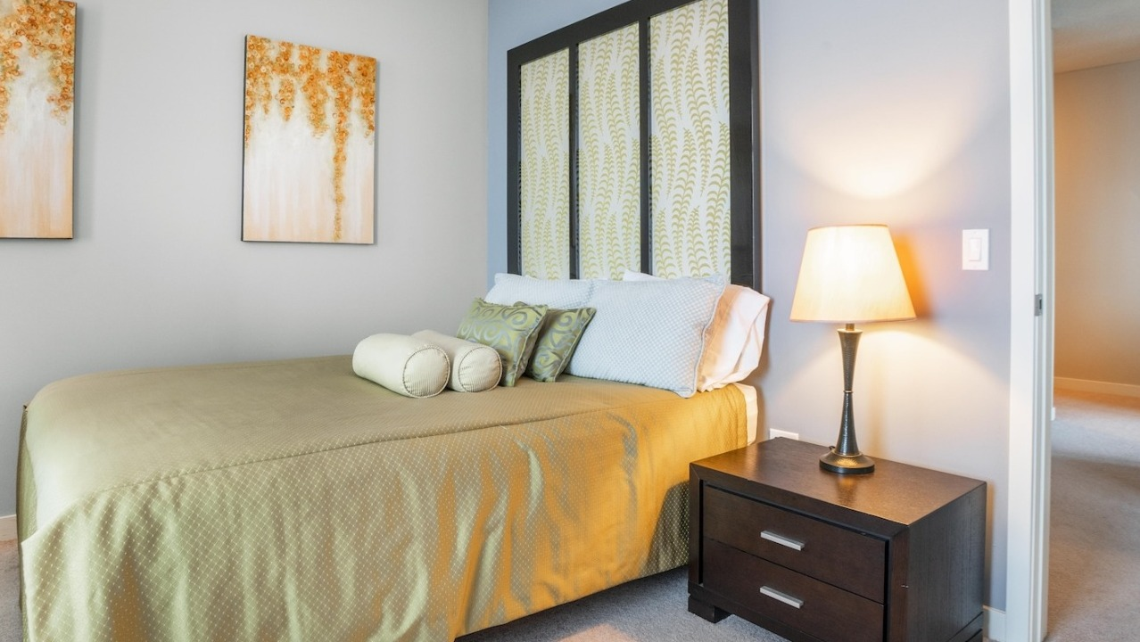 Tranquil bedroom at Alta at K Station with soft blue walls, warm bedside lighting, patterned art, and coordinated bedding for a relaxing retreat