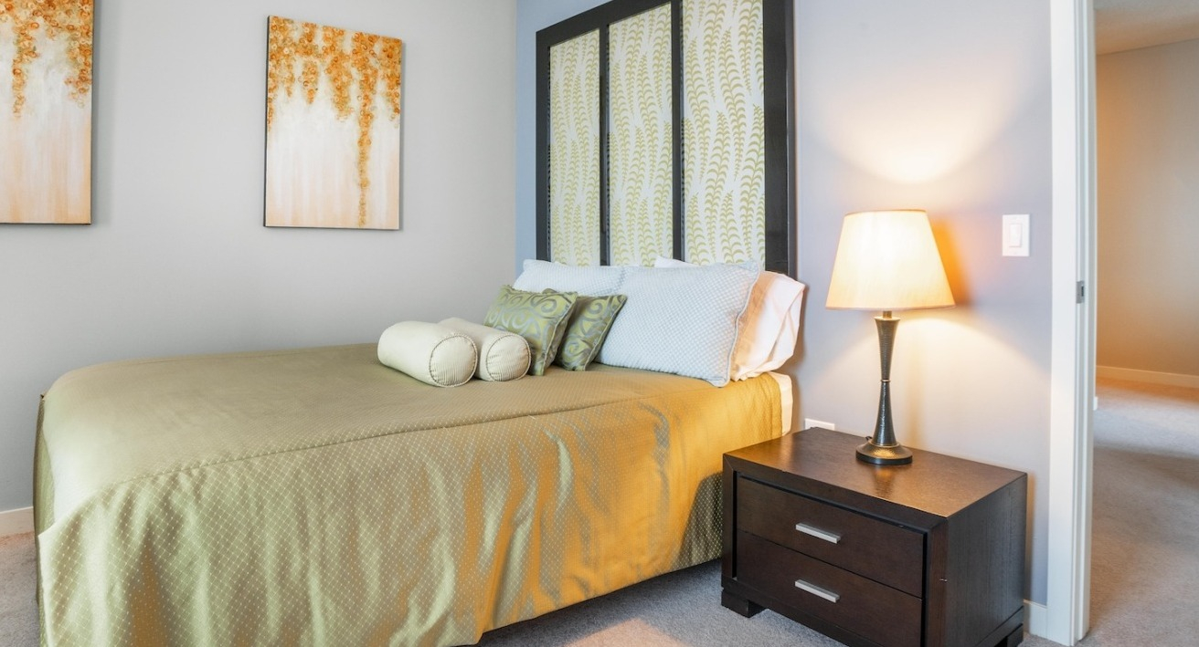 Tranquil bedroom at Alta at K Station with soft blue walls, warm bedside lighting, patterned art, and coordinated bedding for a relaxing retreat