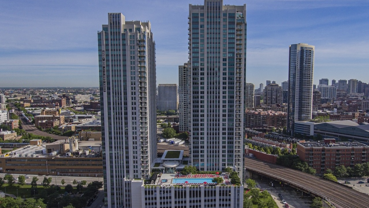 Aerial view of Alta at K Station’s twin high-rise apartment towers with a landscaped rooftop pool deck, set near transit in downtown Chicago