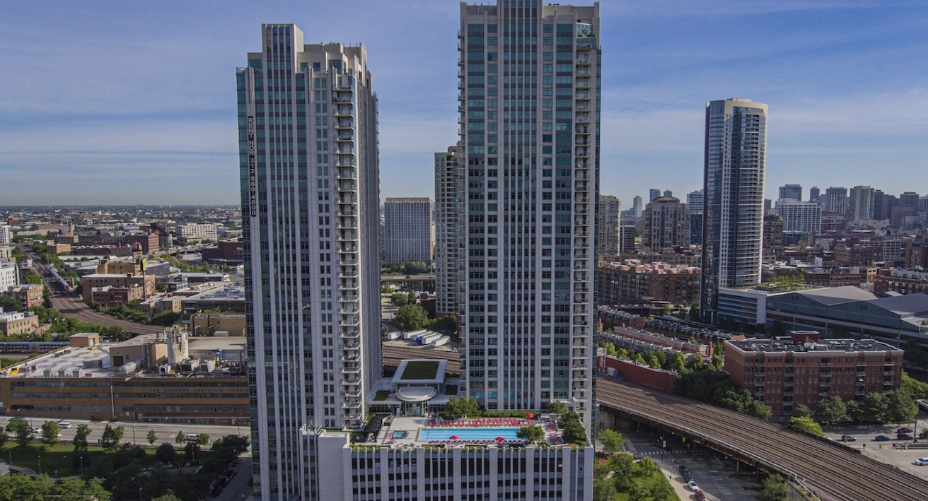 Aerial view of Alta at K Station’s twin high-rise apartment towers with a landscaped rooftop pool deck, set near transit in downtown Chicago