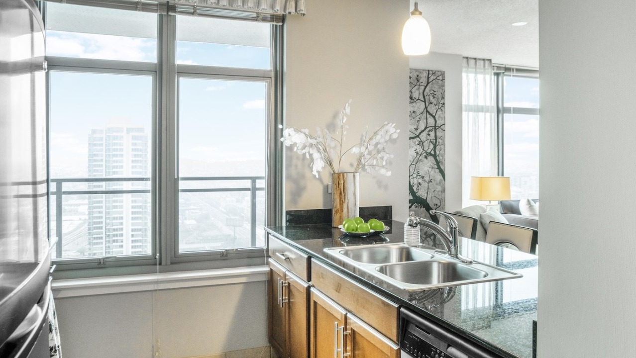 Modern kitchen at Alta at K Station with granite countertops, double sink, stainless appliances, pendant lighting, and window views over Chicago