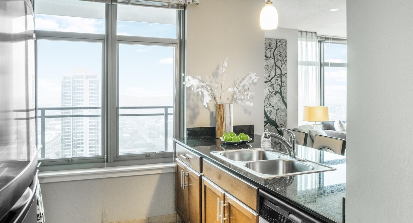 Modern kitchen at Alta at K Station with granite countertops, double sink, stainless appliances, pendant lighting, and window views over Chicago
