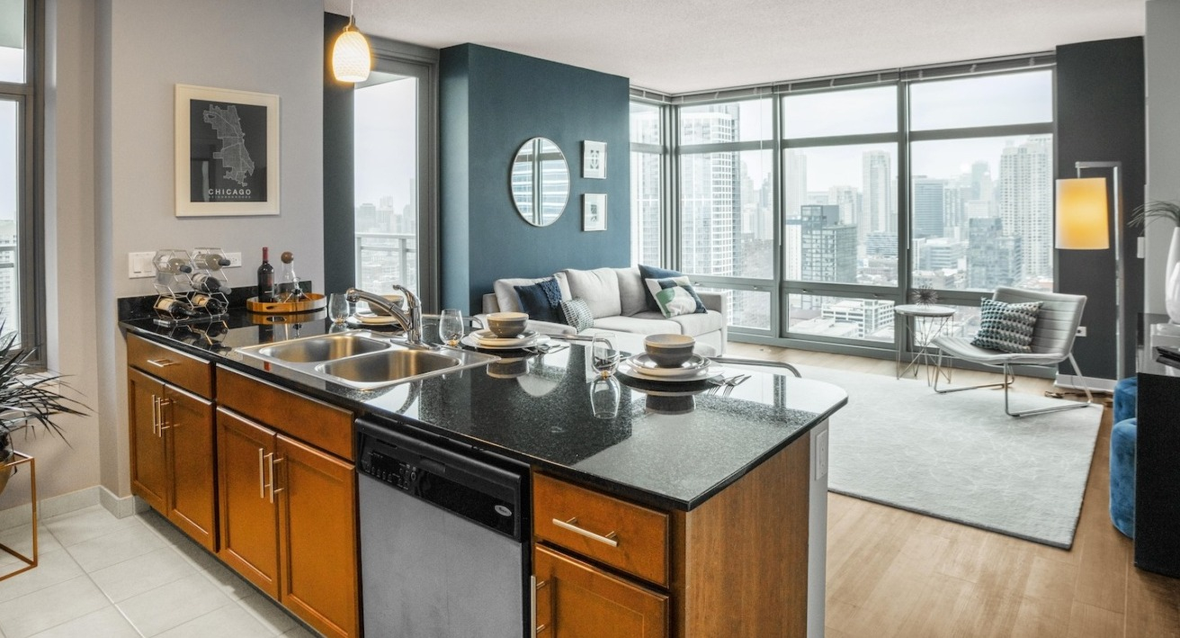 Open-concept kitchen at Alta at K Station featuring a granite island with sink, tile flooring, and sightlines to a bright living area with city views