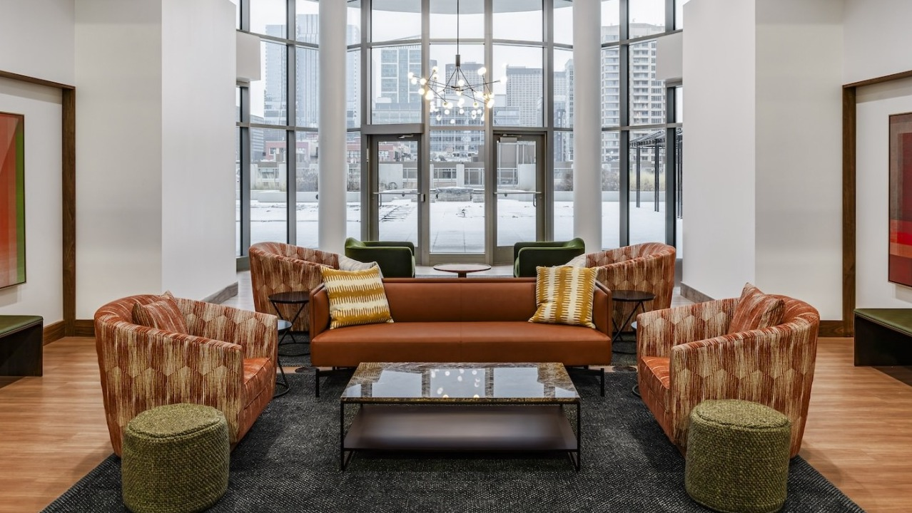 Stylish lobby lounge at Alta at K Station featuring floor-to-ceiling windows, vibrant seating, modern art, and warm wood flooring