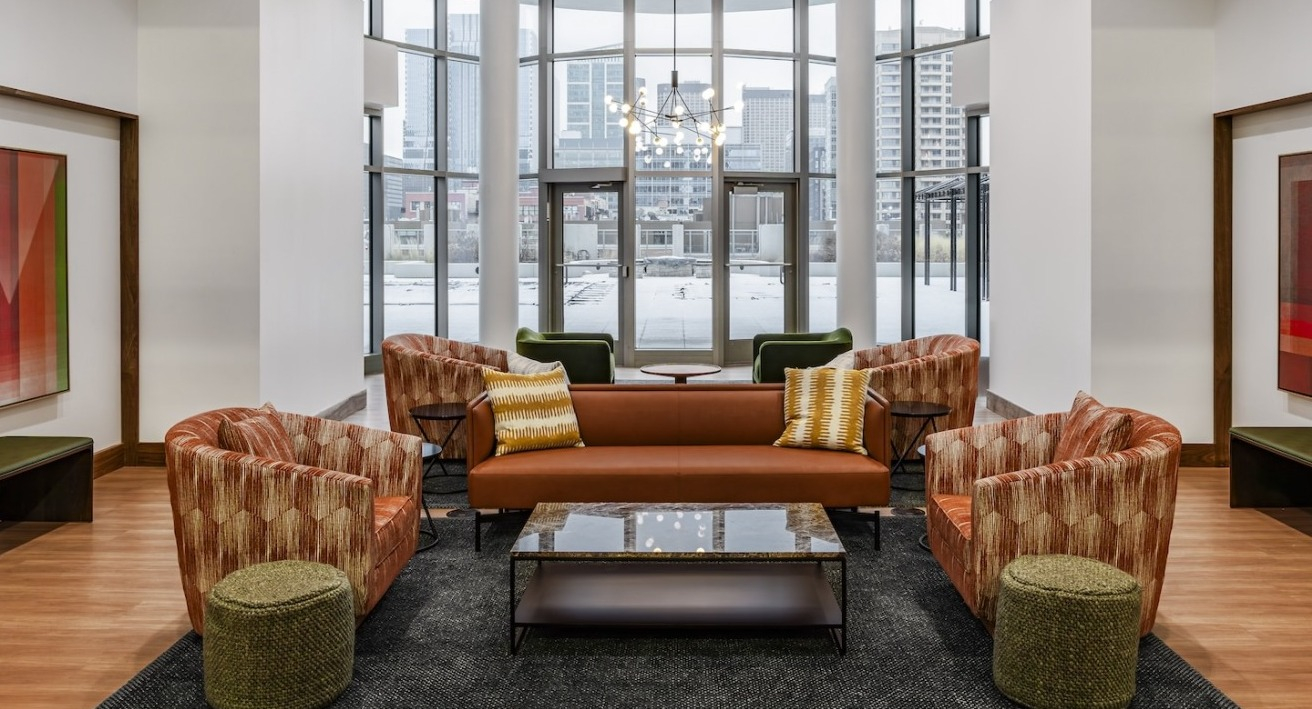 Stylish lobby lounge at Alta at K Station featuring floor-to-ceiling windows, vibrant seating, modern art, and warm wood flooring