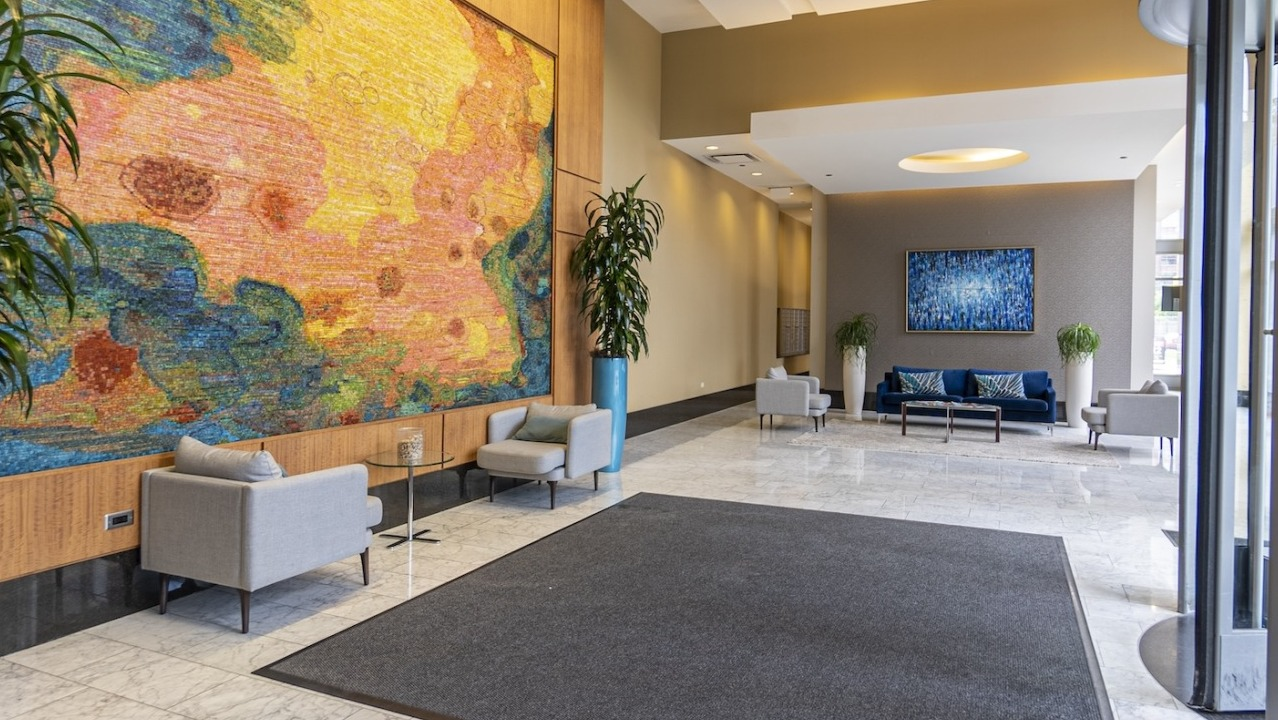 Bright lobby at Alta at K Station with a colorful art wall, modern seating, tall ceilings, and polished stone floors for a welcoming first impression