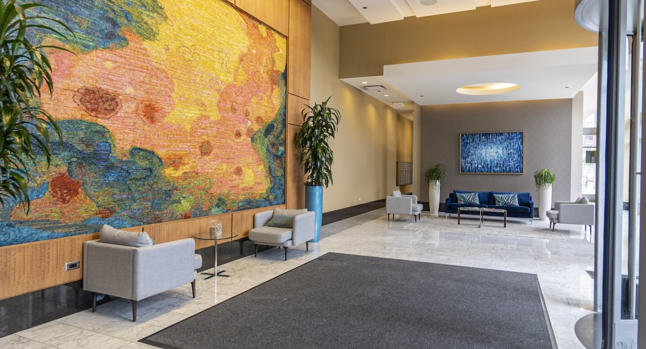 Bright lobby at Alta at K Station with a colorful art wall, modern seating, tall ceilings, and polished stone floors for a welcoming first impression
