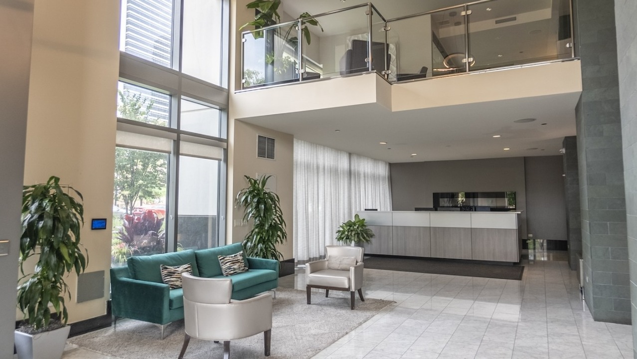 Resident lobby and reception at Alta at K Station with double-height windows, a modern front desk, contemporary seating, and elegant marble flooring