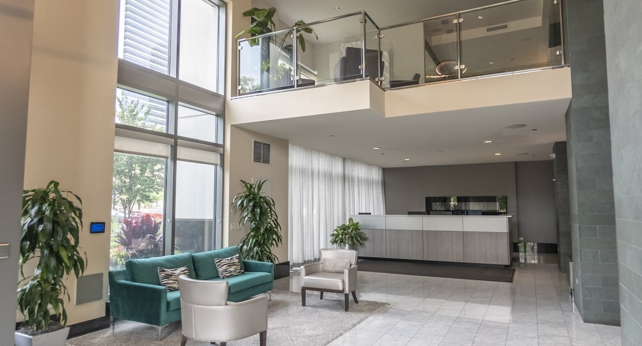 Resident lobby and reception at Alta at K Station with double-height windows, a modern front desk, contemporary seating, and elegant marble flooring
