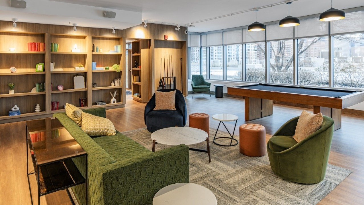 Spacious resident lounge at Alta at K Station featuring billiards table, bookshelves, modern seating, and large windows with natural light