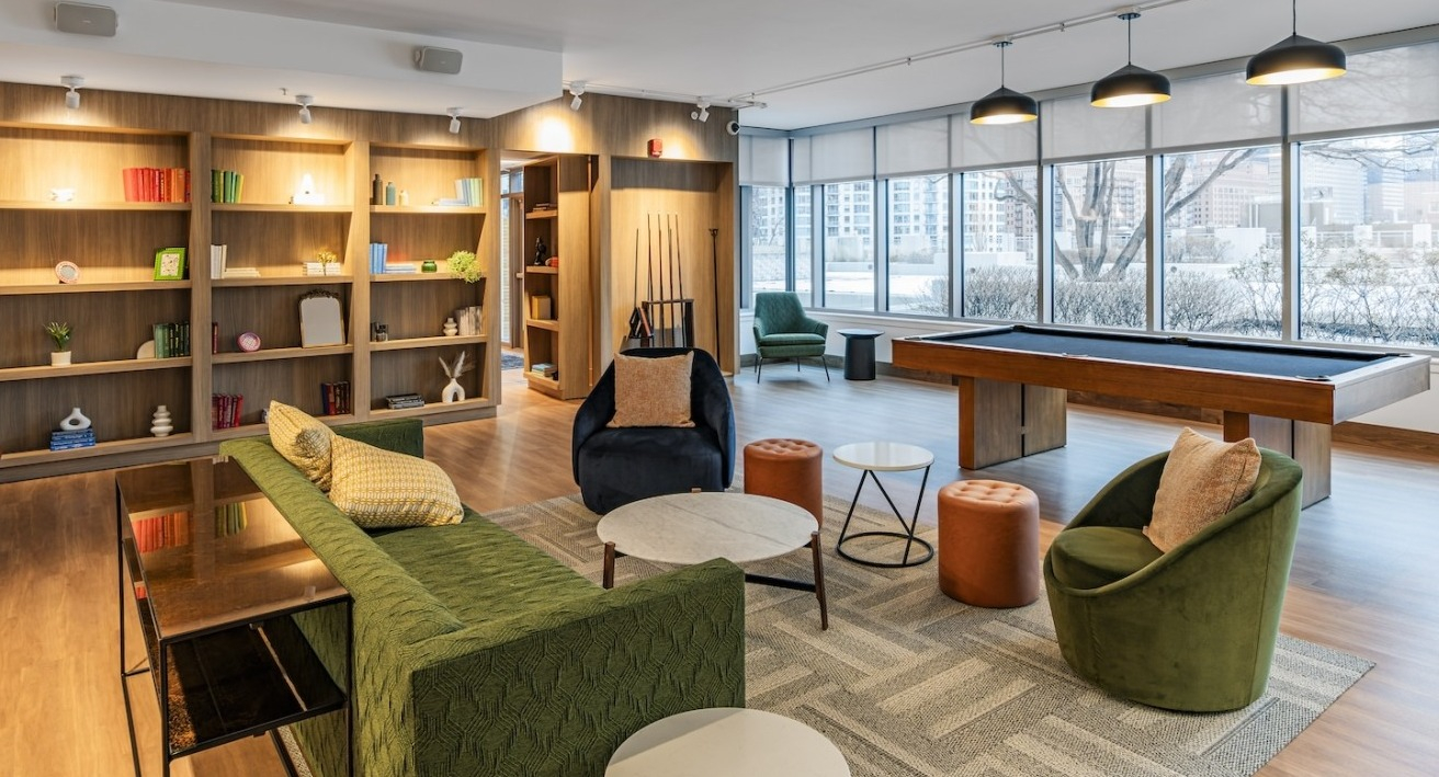 Spacious resident lounge at Alta at K Station featuring billiards table, bookshelves, modern seating, and large windows with natural light